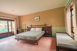 A bedroom with a bed, a bedside table, a chair, a window with curtains, and a picture on the wall. - Dreamville Beach Homestay (Hoa Hiep)