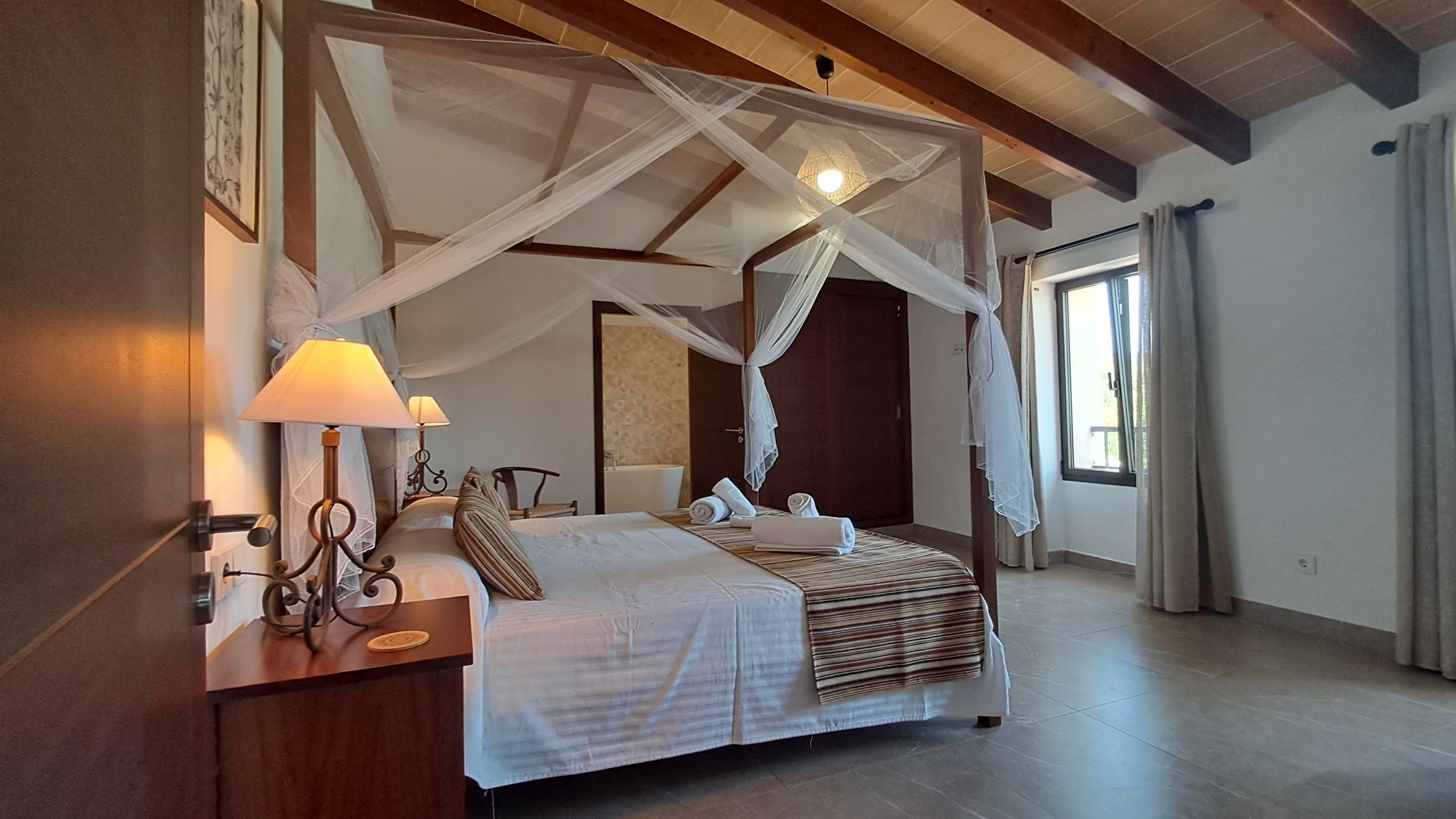 Un letto a baldacchino con un'elegante testiera in legno, lampade ai comodini e asciugamani piegati con cura.