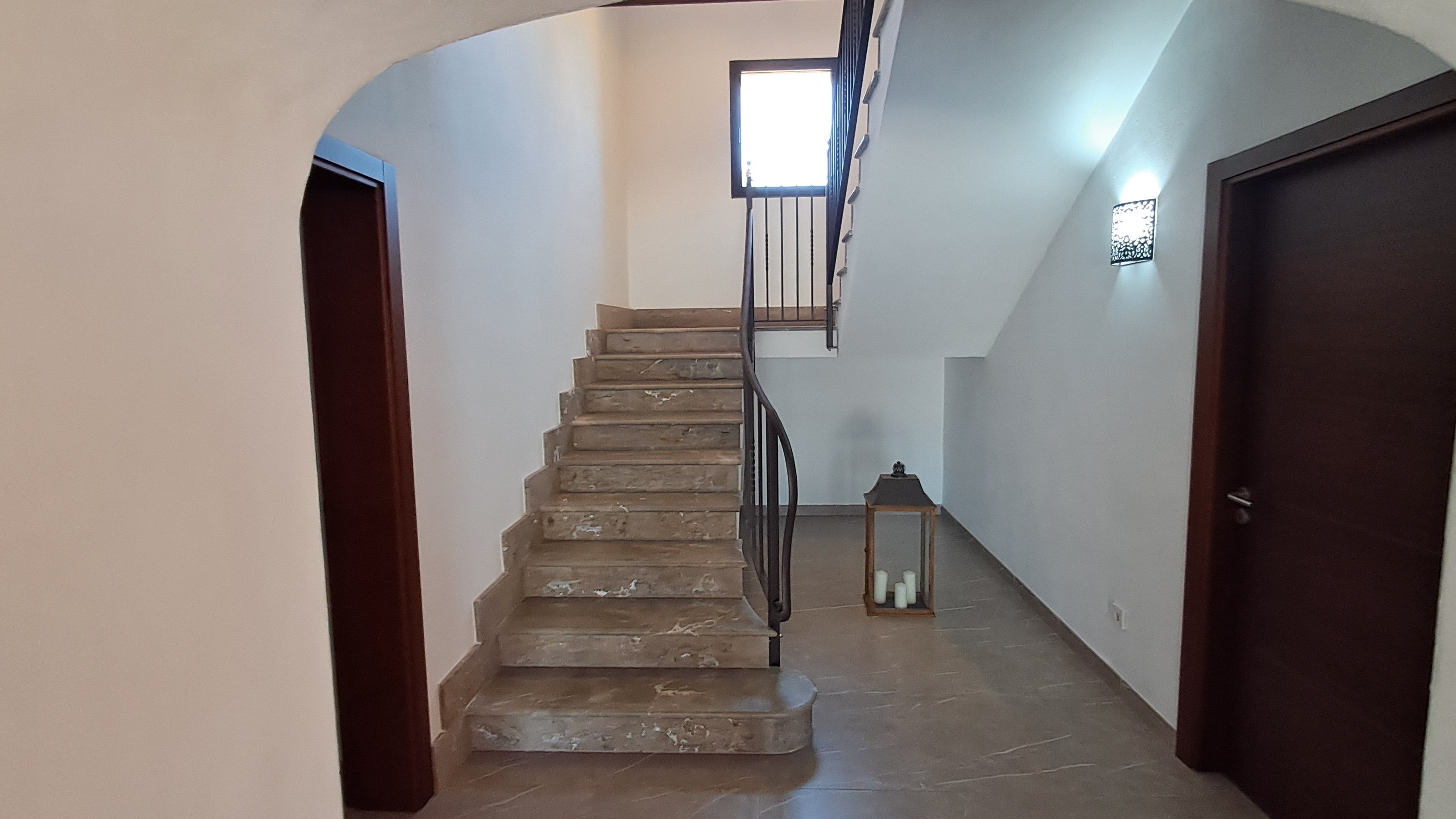 Eine Treppe mit Handlauf, ein kleiner Tisch mit Kerzen und eine Tür rechts.
