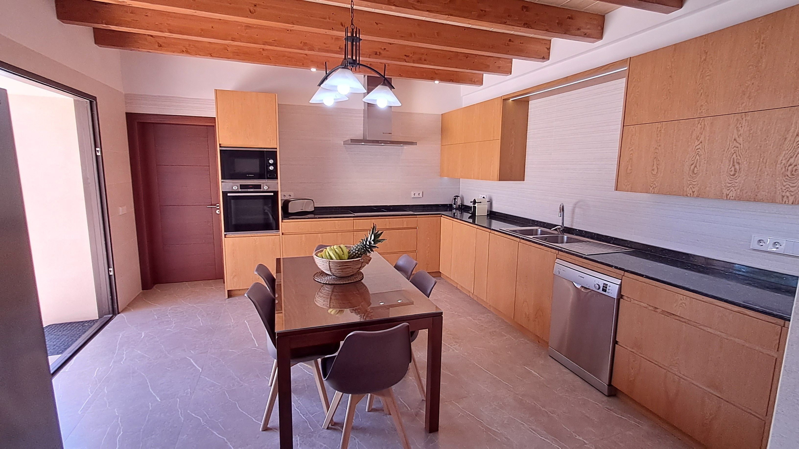 Une cuisine moderne avec des meubles en bois, un four encastré, un four à micro-ondes et un lave-vaisselle.