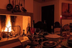 Una stanza accogliente con camino, tavolo imbandito con piatti, bicchieri e posate.