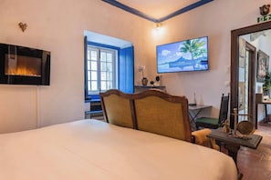 Quarto com uma cama, televisão fixada na parede, janela e porta.