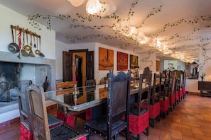 Uma sala de jantar com uma mesa grande, cadeiras e uma lareira.