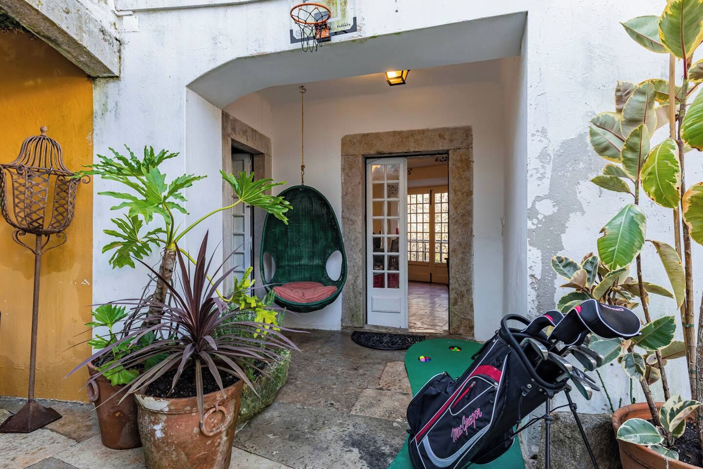A courtyard with potted plants, a hanging chair, and a bicycle rack.
