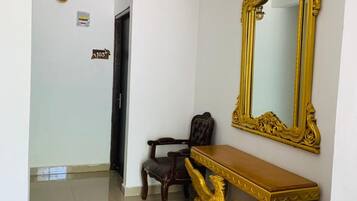 Un pasillo con un espejo dorado ornamentado, una consola de madera y un sillón de cuero.