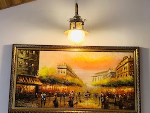 Un cuadro enmarco muestra una escena callejera histórica con edificios y gente, colgado en una pared.