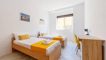 Une chambre d’hôtel avec deux lits, un bureau et une chaise.