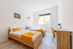 A hotel room with two beds, a desk, and a chair. - RODOLFU F5A (Tas-Sliema)