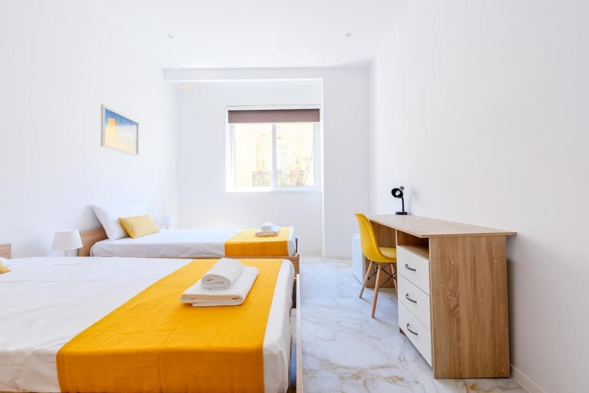 Una habitación de hotel con dos camas, un escritorio y una ventana.