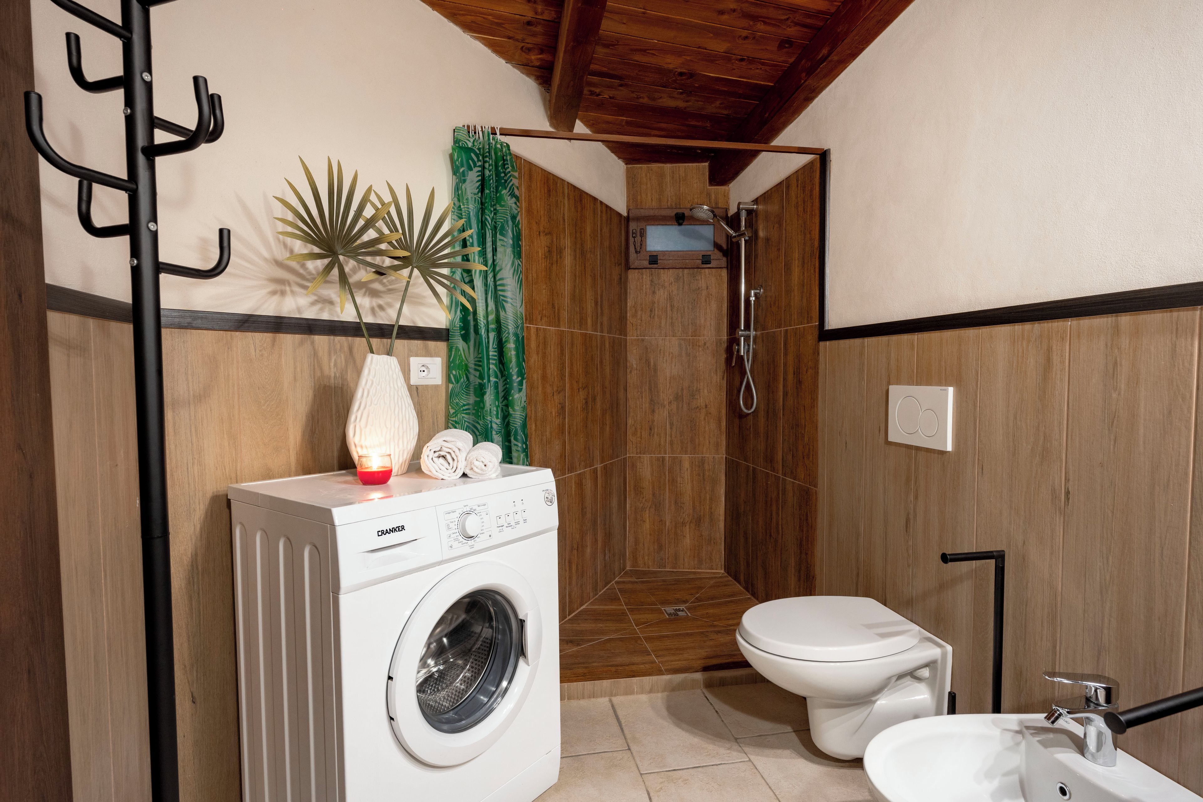 Une petite salle de bain équipée d’un lave-linge, de toilettes et d’une douche.
