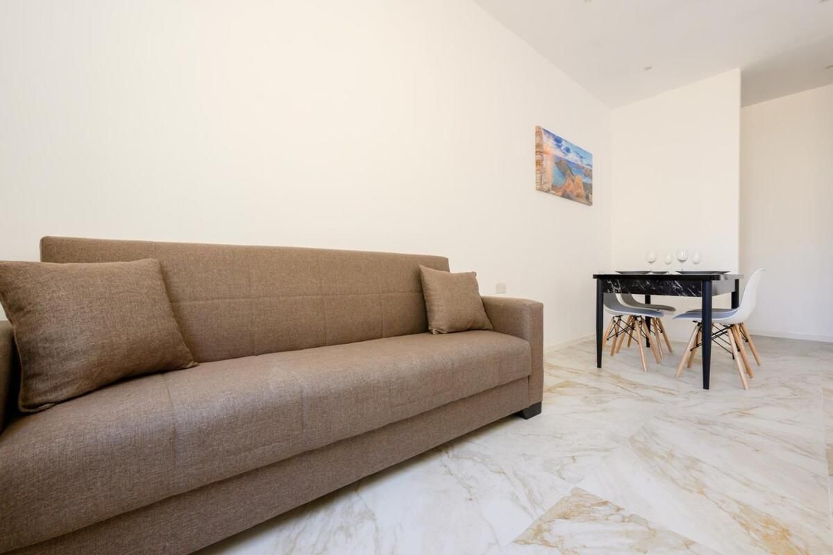 Una sala de estar con un sofá y una mesa de comedor con sillas.