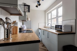 Una cucina moderna con piano di lavoro in legno, elettrodomestici in acciaio inossidabile e una finestra che lascia entrare luce naturale.