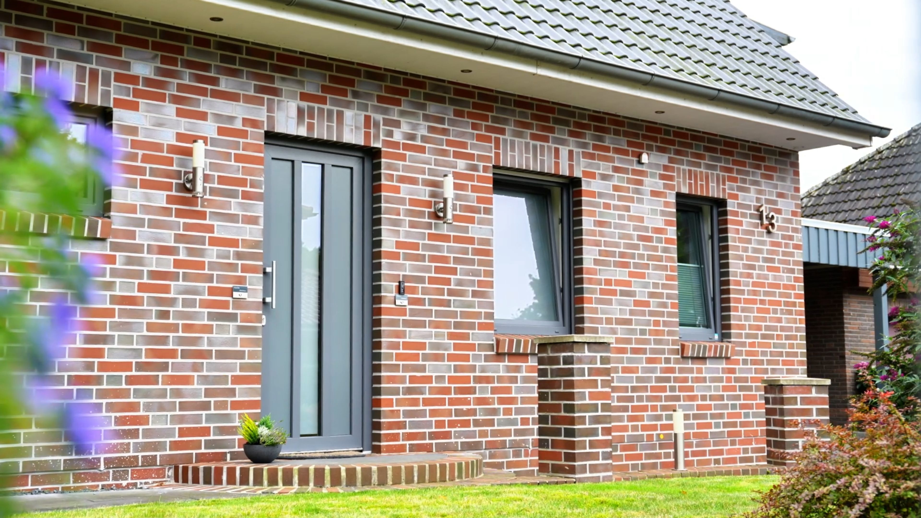 A brick house with a grey door, a small porch, and a window.