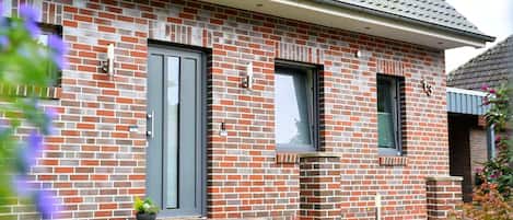 A brick house with a grey door, a small porch, and a window.