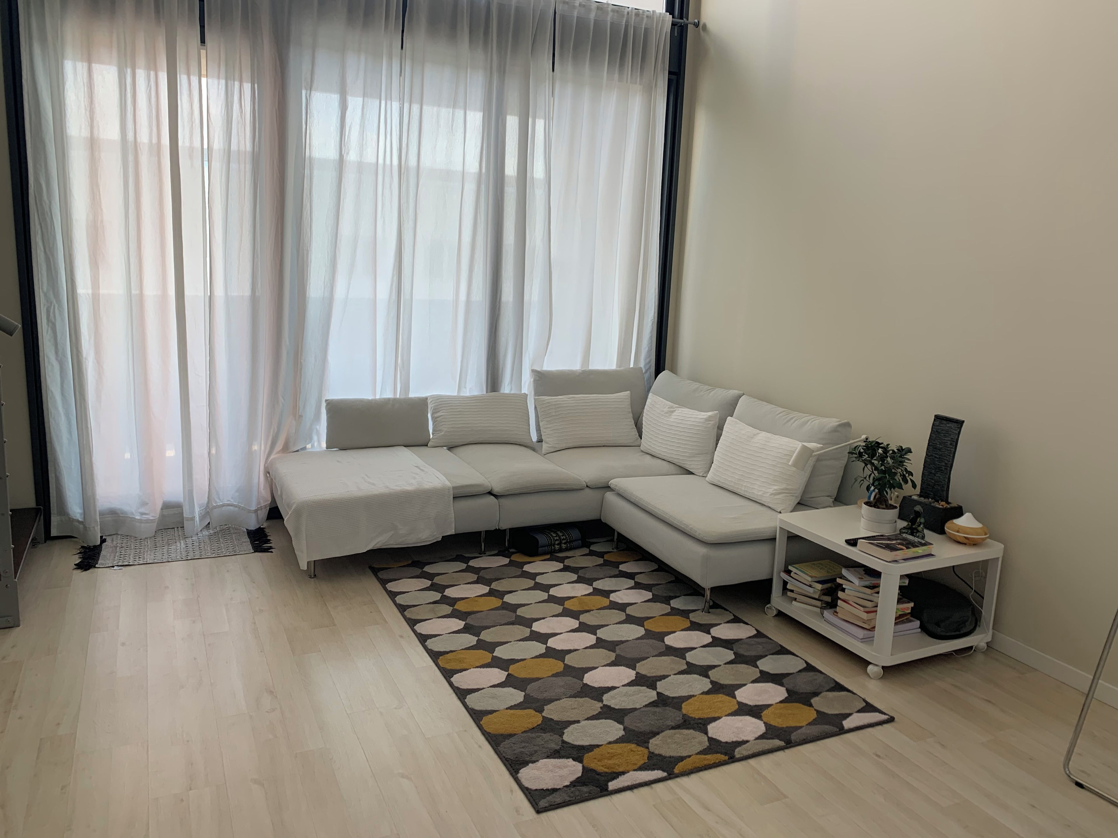 Un salon moderne avec un canapé d’angle, une table basse et une bibliothèque.