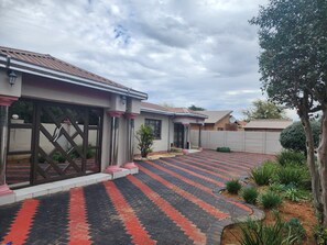 Propiedad residencial con camino de entrada pavimentado, acceso por portón y un pequeño jardín.