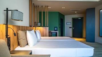 Una habitación de hotel moderna con una cama grande, un sofá, un escritorio y vistas al pasillo.