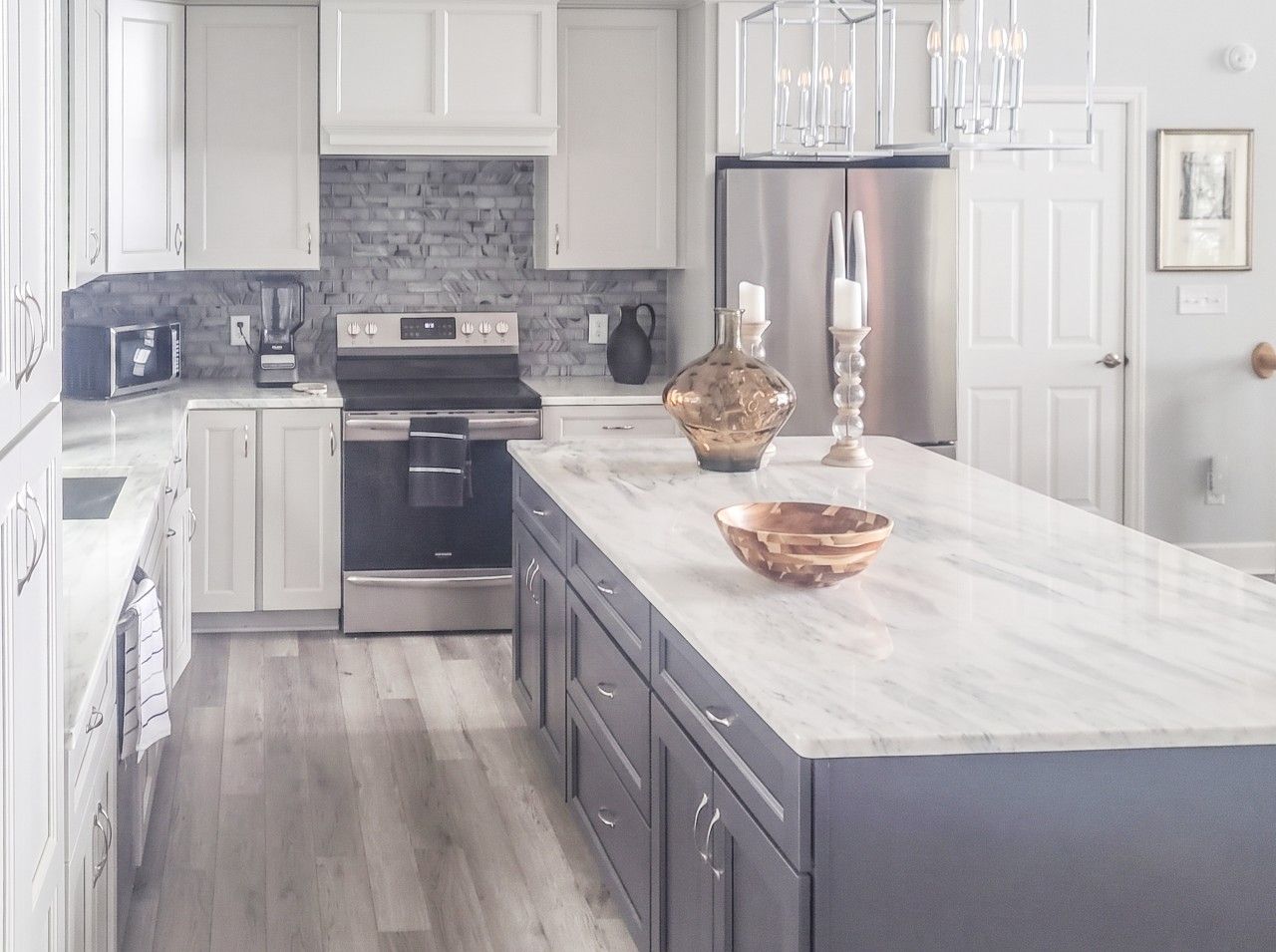Una cocina moderna con armarios blancos, encimera de mármol y electrodomésticos de acero inoxidable.