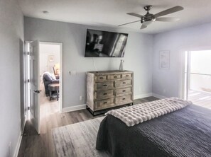 A bedroom with a bed, a dresser, a television, and a door leading to another room. - 5-Bedroom, 4-Bathroom A-Frame Mountain House (Roaring Gap)