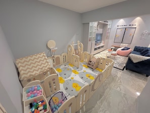 A child's play area with a table, chairs, and a playpen. - 22Pax PJ Karaoke & PS5 Landed Homestay by 4Balance (Petaling Jaya)