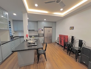 A modern kitchen with a central island, stainless steel appliances, and a dining area with chairs. - 22Pax PJ Karaoke & PS5 Landed Homestay by 4Balance (Petaling Jaya)