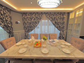 A dining room with a marble table set for six, surrounded by upholstered chairs. - 22Pax PJ Karaoke & PS5 Landed Homestay by 4Balance (Petaling Jaya)