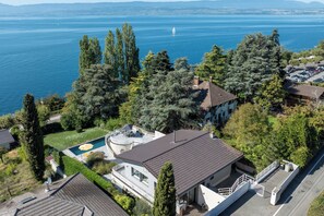 Un barrio residencial con piscina, una casa grande de teja y vistas a un lago.