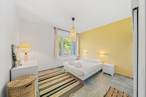 Un dormitorio moderno con cama, mesitas de noche, lámpara colgante y vistas al exterior.