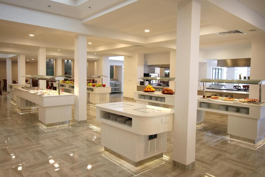A modern hotel dining area with multiple buffet stations, high ceilings, and a polished floor.