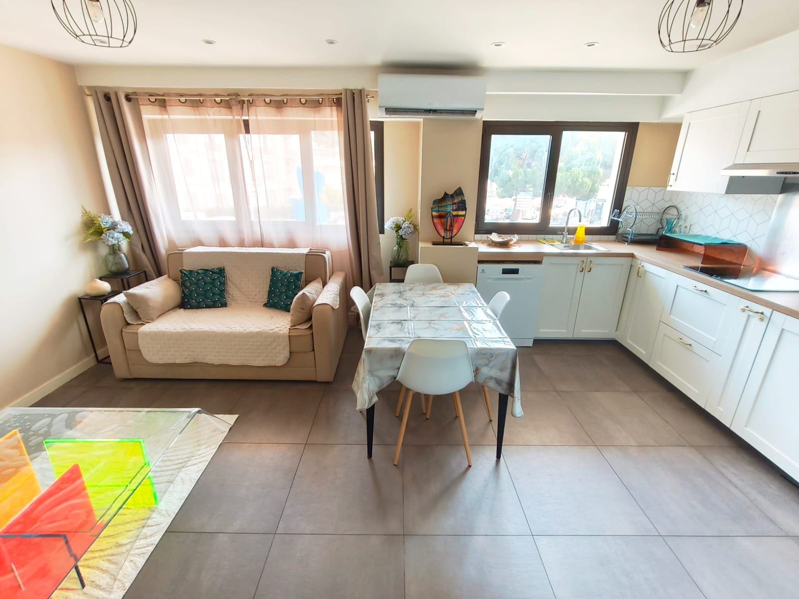A modern living room with a sofa, dining table, and kitchen area.