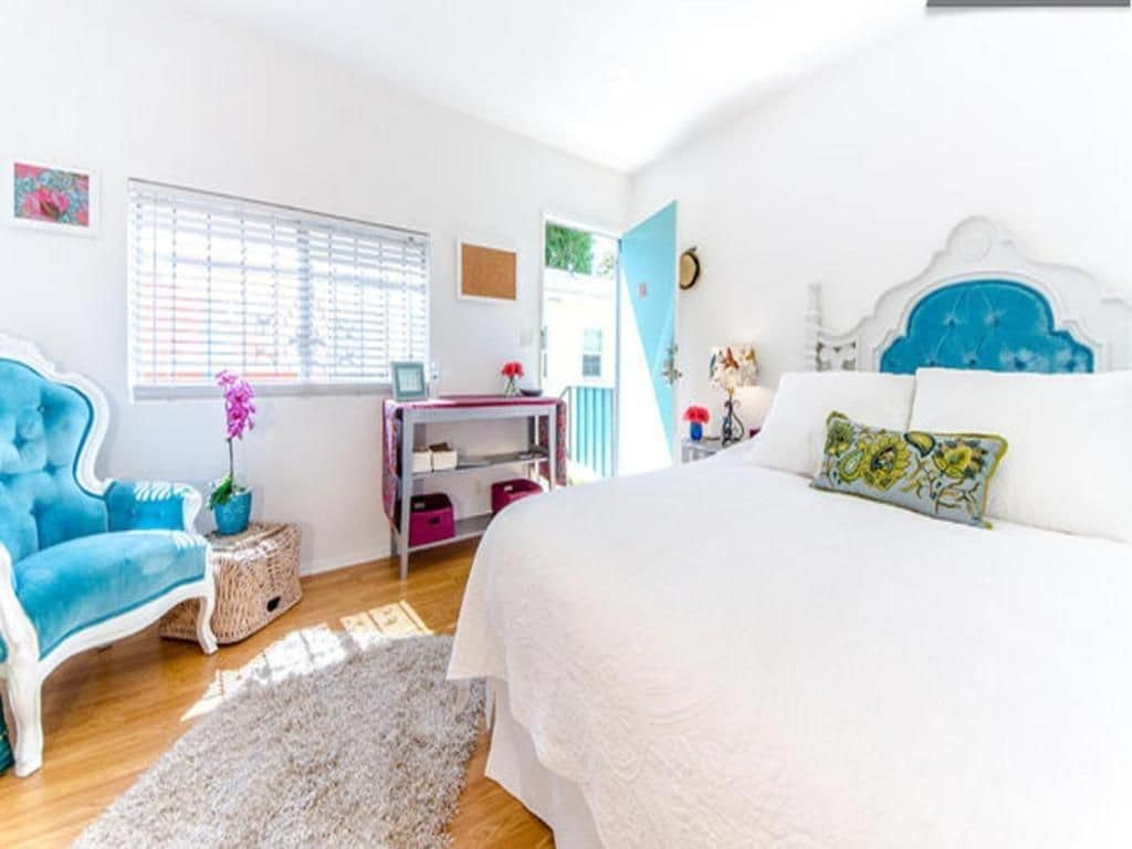 A bedroom with a bed, a chair, a desk, and a window.