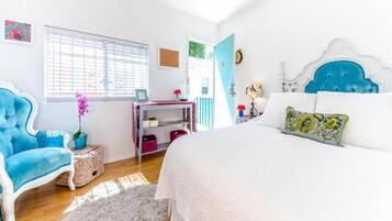 A bedroom with a bed, a chair, a desk, and a window.