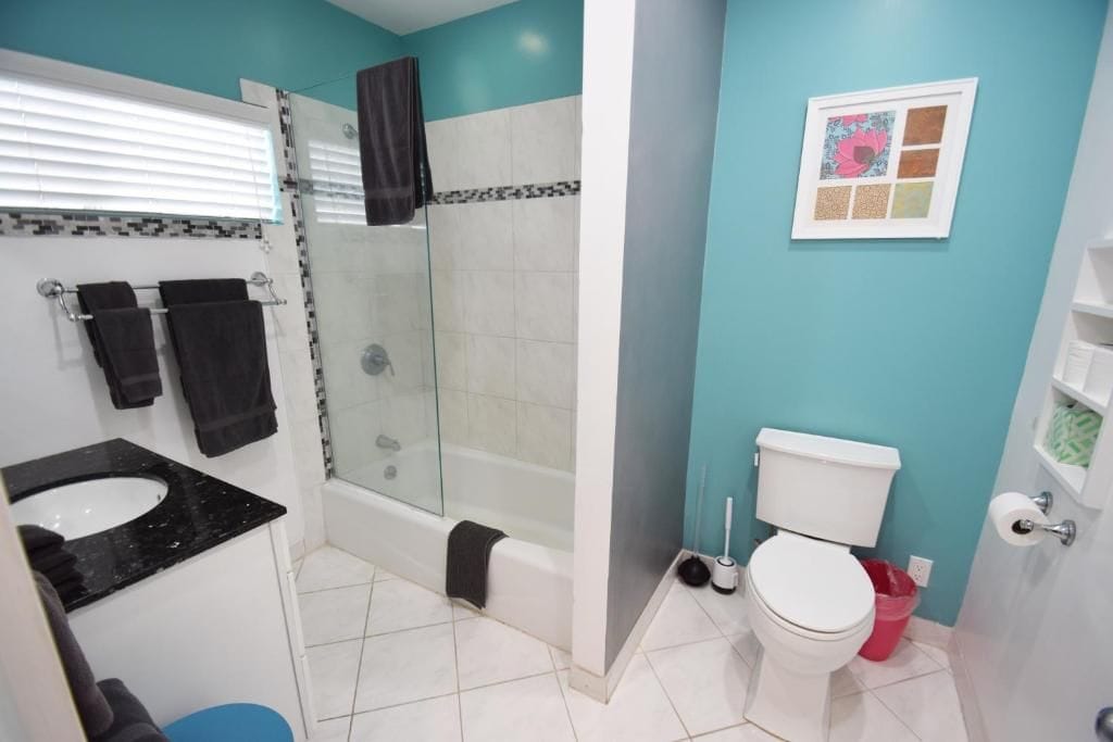 A bathroom with a glass-enclosed shower, a white toilet, and a black sink.