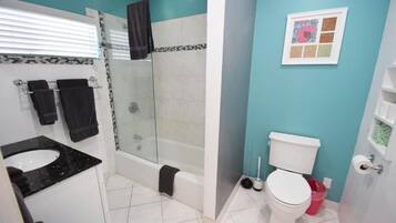 A bathroom with a glass-enclosed shower, a white toilet, and a black sink.