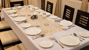 Una mesa de comedor bien dispuesta con mantel blanco, platos, cubiertos y vasos.