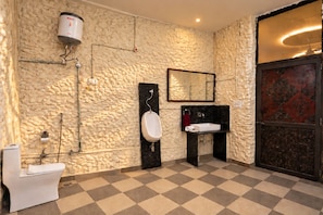 Un bany amb una paret amb relleu, un orinal, un lavabo i un vàter.