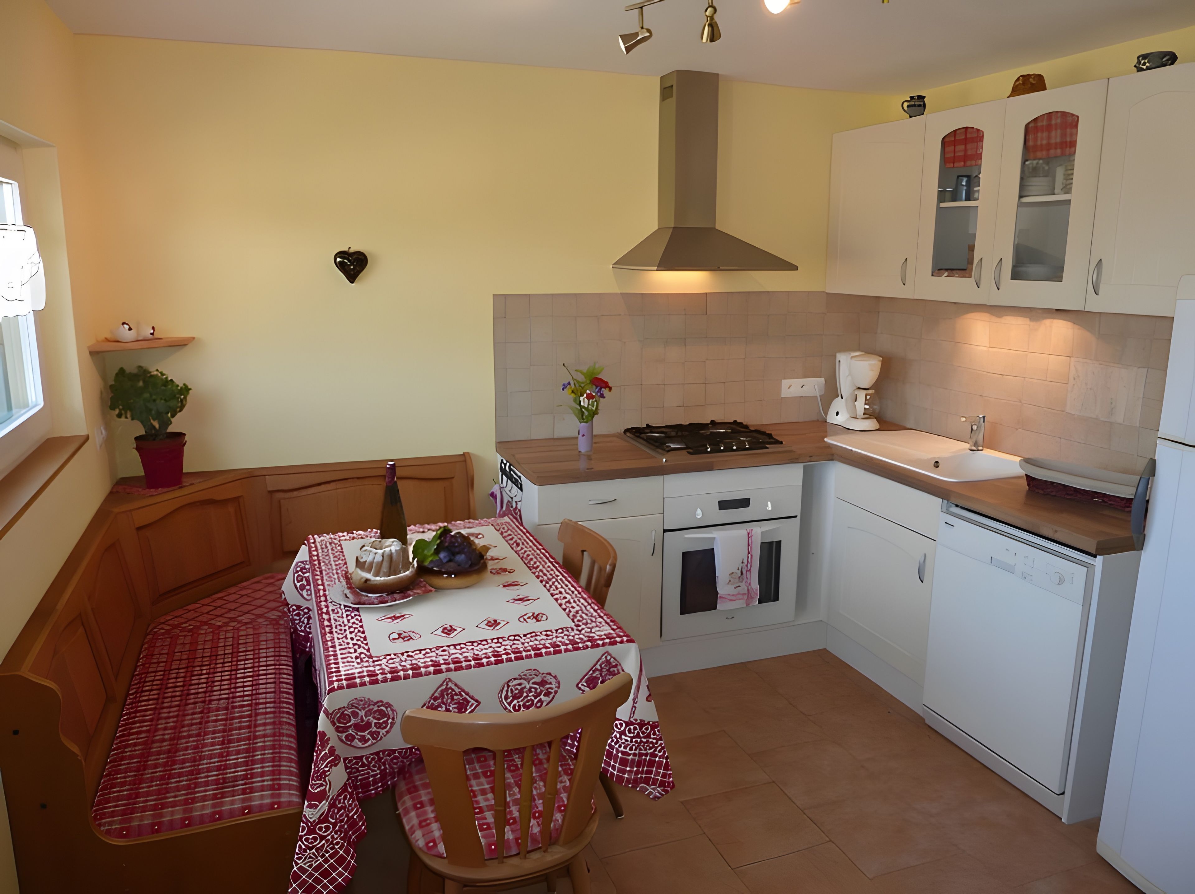 Una cocina compacta con comedor, estufa a gas, horno empotrado y muebles de cocina blancos.