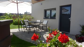 Un patio moderno al aire libre con una mesa, sillas, una puerta y vistas del entorno.
