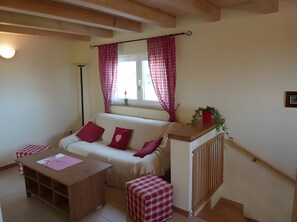 A cozy room with a white sofa, red cushions, a wooden table, and a radiator.