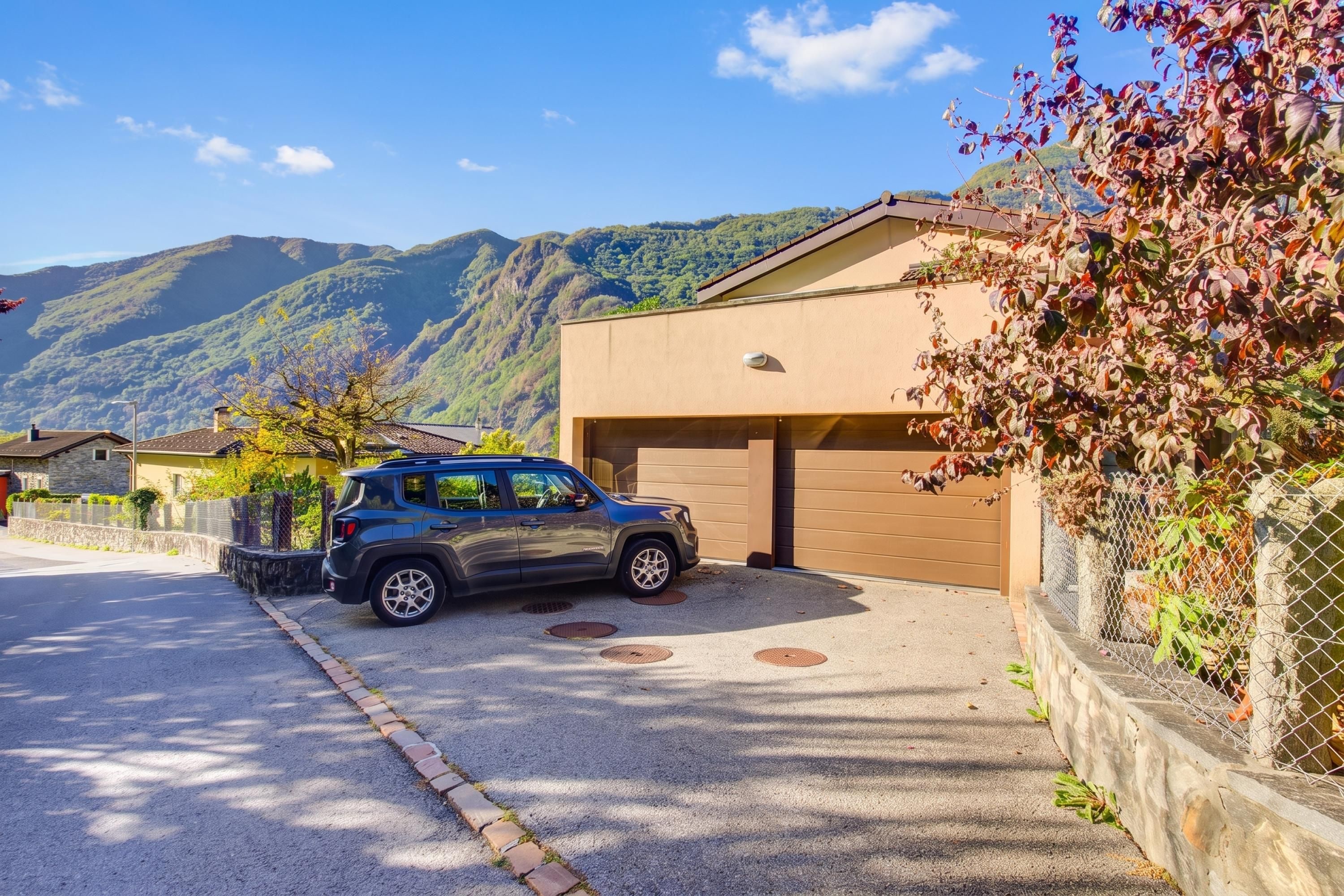 A residential area with a parked SUV, a garage, and a house with a mountain backdrop.