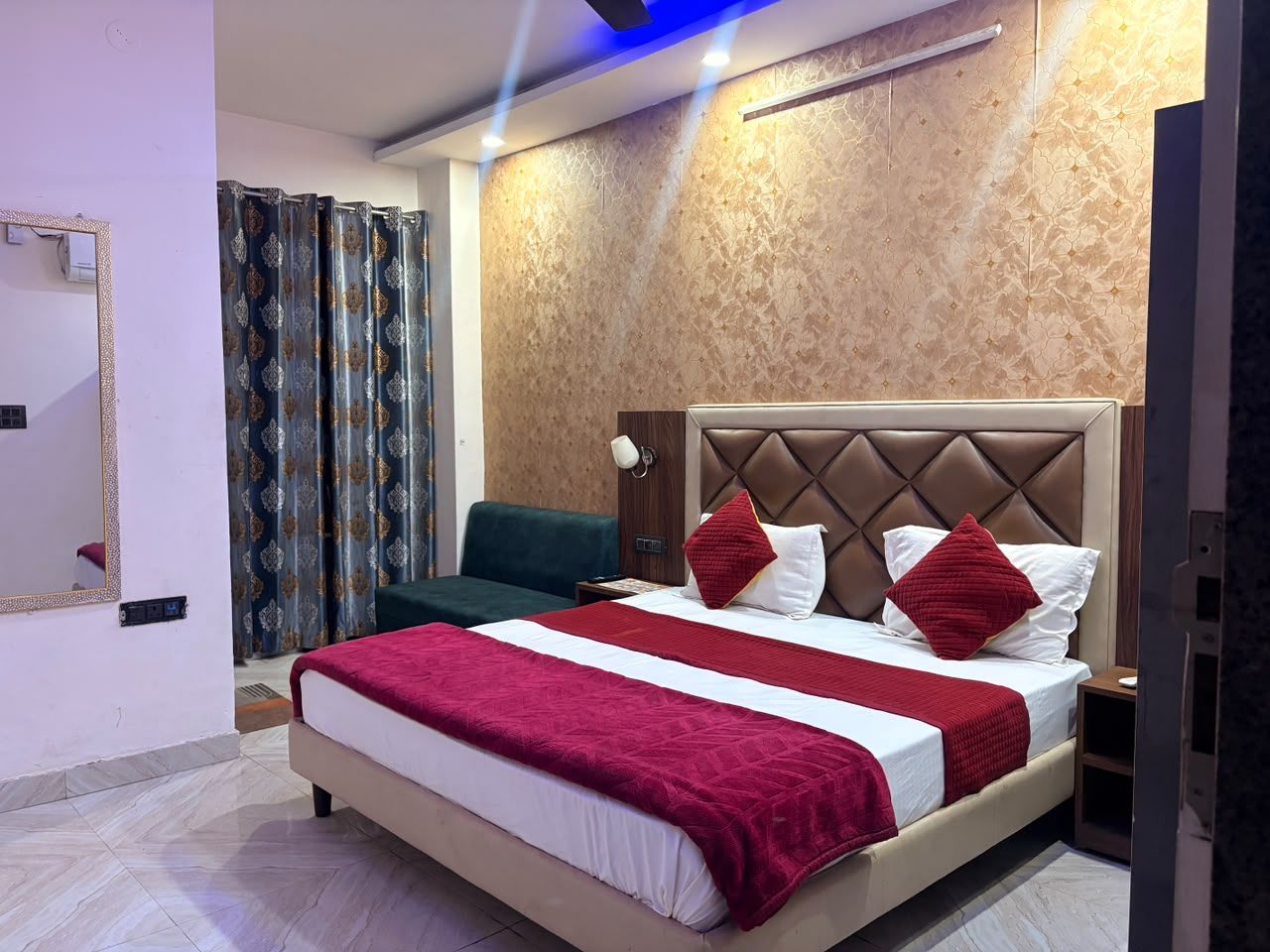 Habitación de hotel con una cama grande, una mesita de noche, un espejo y una ventana con cortinas.