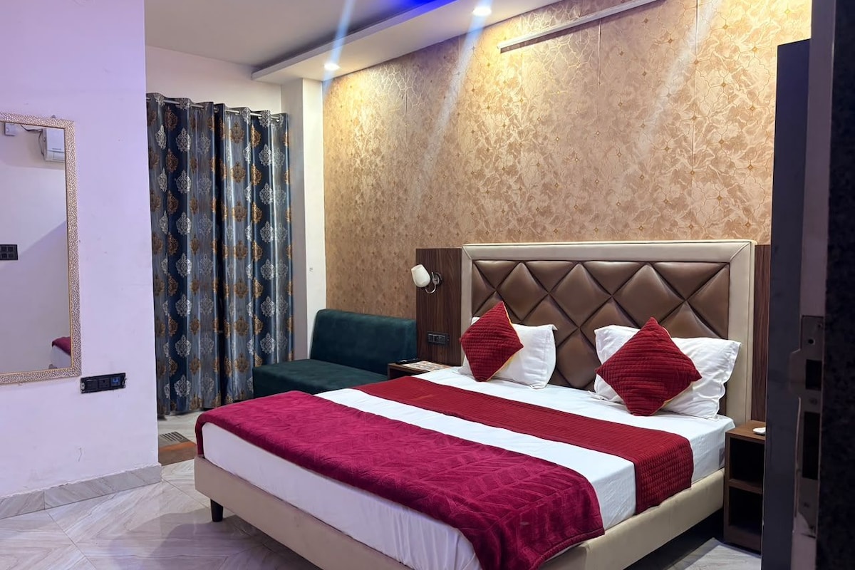 Habitación de hotel con una cama grande, una mesita de noche, un espejo y una ventana con cortinas.