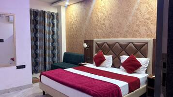Habitación de hotel con una cama grande, una mesita de noche, un espejo y una ventana con cortinas.
