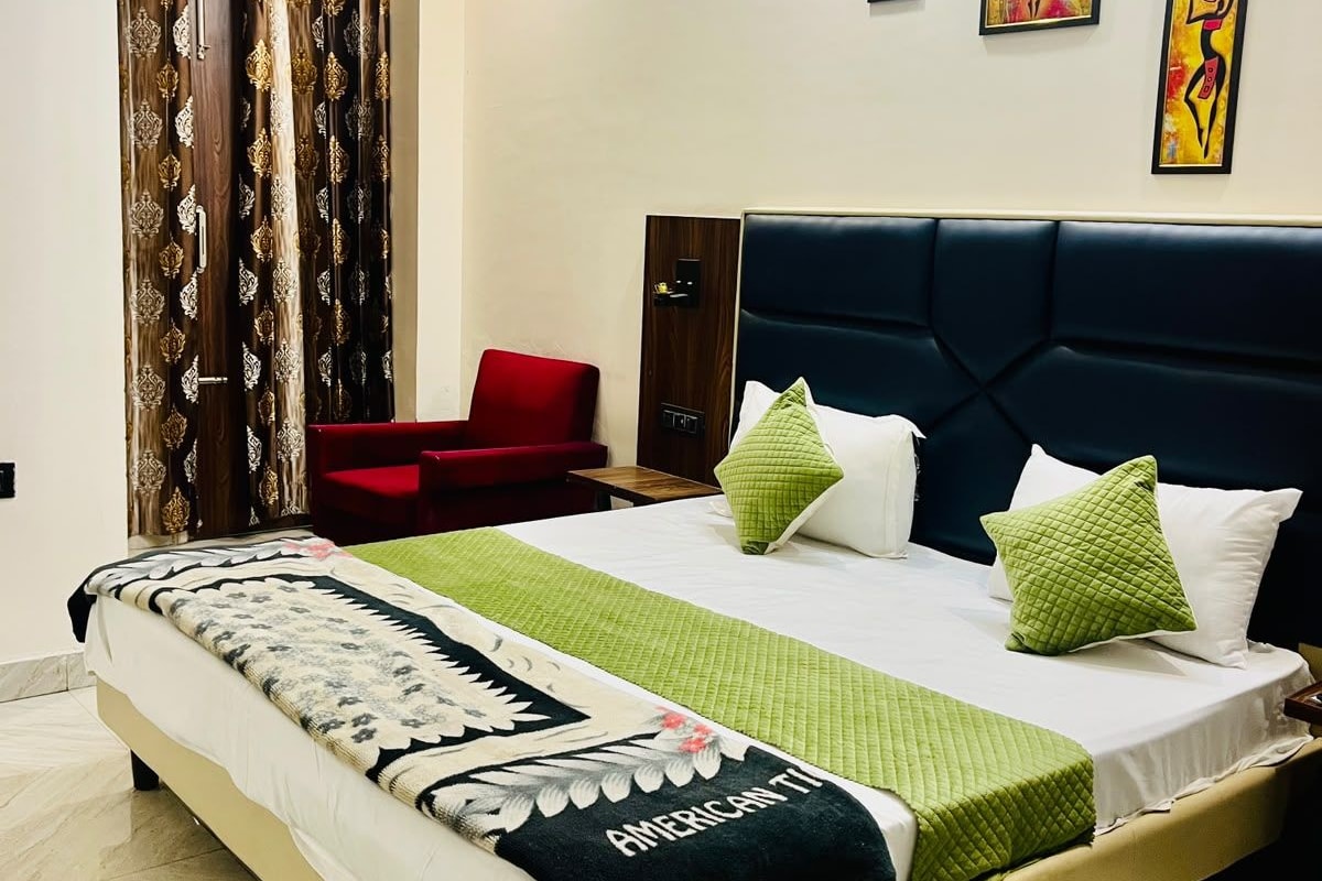 Una habitación de hotel con una cama grande, una silla roja, una puerta de madera y arte abstracto en la pared.
