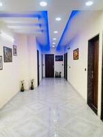A hallway with a herringbone floor pattern, recessed lighting, and wall-mounted artwork.