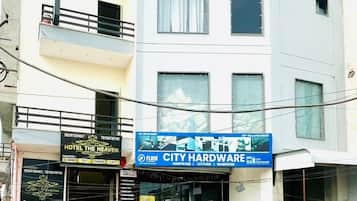 A multi-story hotel named 'Hotel Heaven' with balconies, a signboard, and a storefront for 'City Hardware' below.