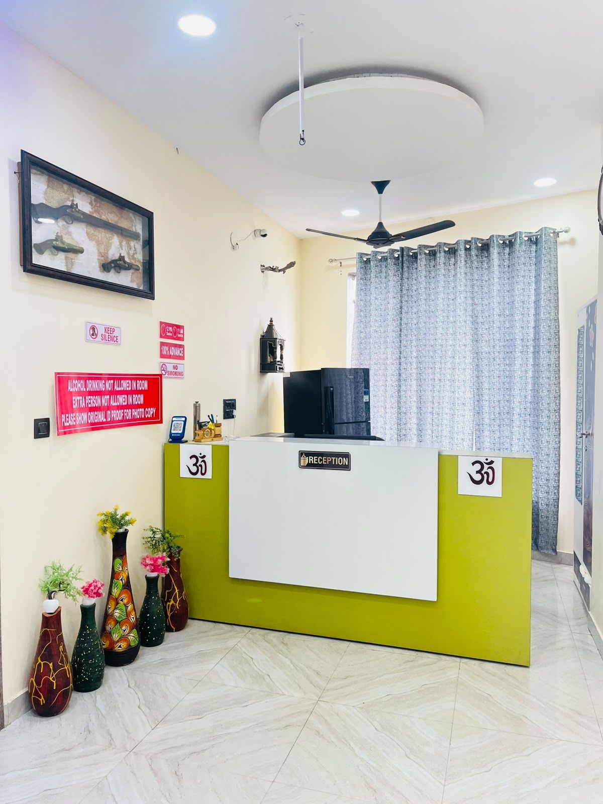 Un mostrador de recepción con un letrero que indica la habitación número 35, un ventilador de techo y un cuadro en la pared.