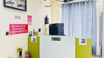 Un mostrador de recepción con un letrero que indica la habitación número 35, un ventilador de techo y un cuadro en la pared.