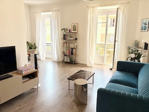 Ein Wohnzimmer mit einer Couch, einem Couchtisch, einem Fernseher und einem Bücherregal.