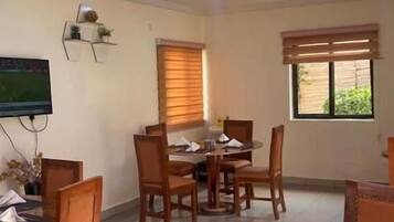 Un comedor con una mesa redonda, sillas y un televisor instalado en la pared.